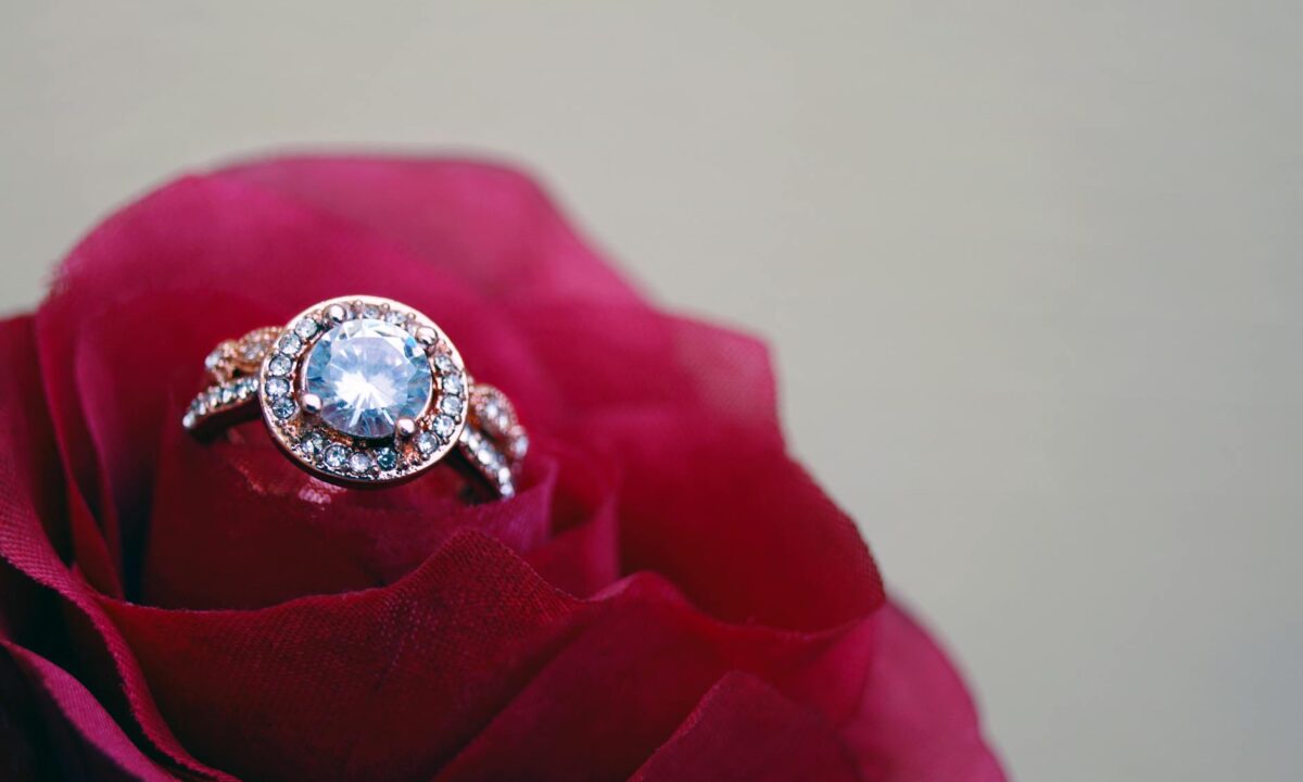 closeup photography of clear jeweled gold colored cluster ring on red rose