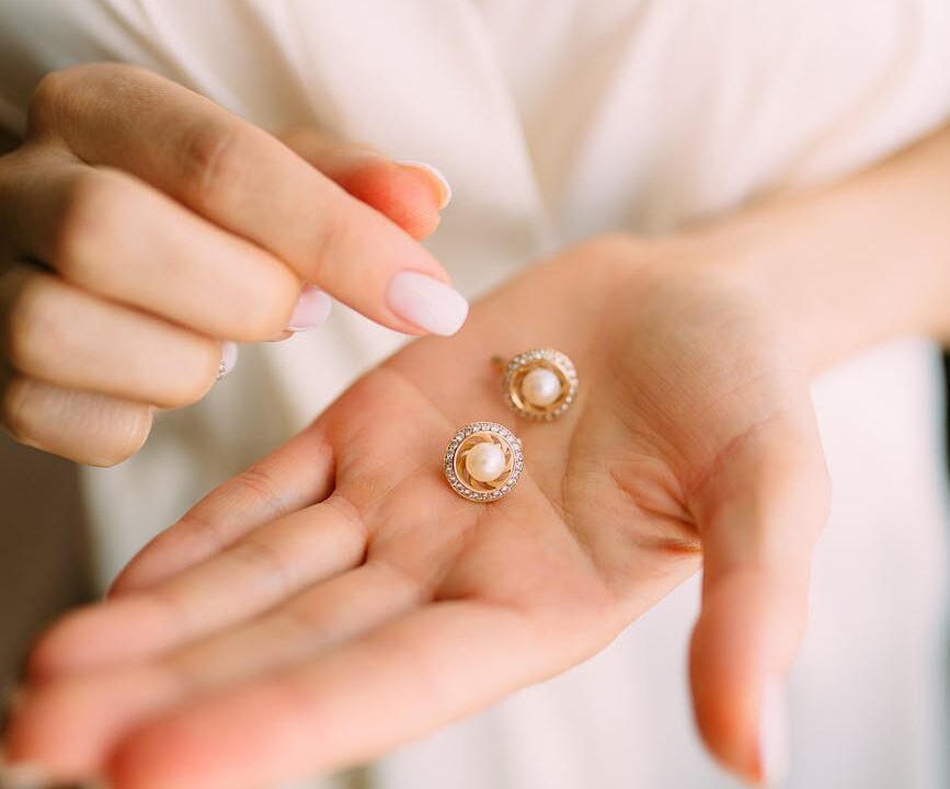 close up photo of person holding earrings