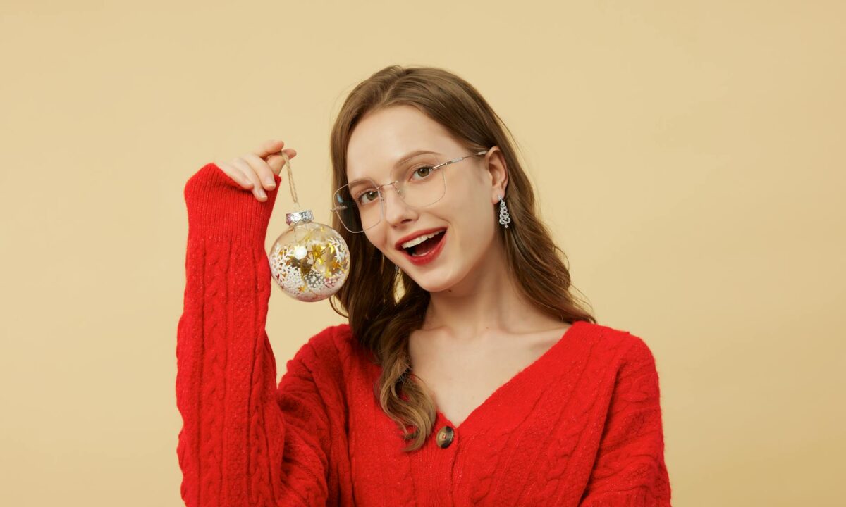 cheerful woman with glasses holding christmas ornament